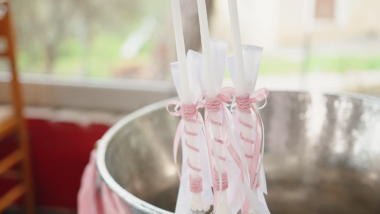 White baptism candle with pink ribbon in serene indoor setting
