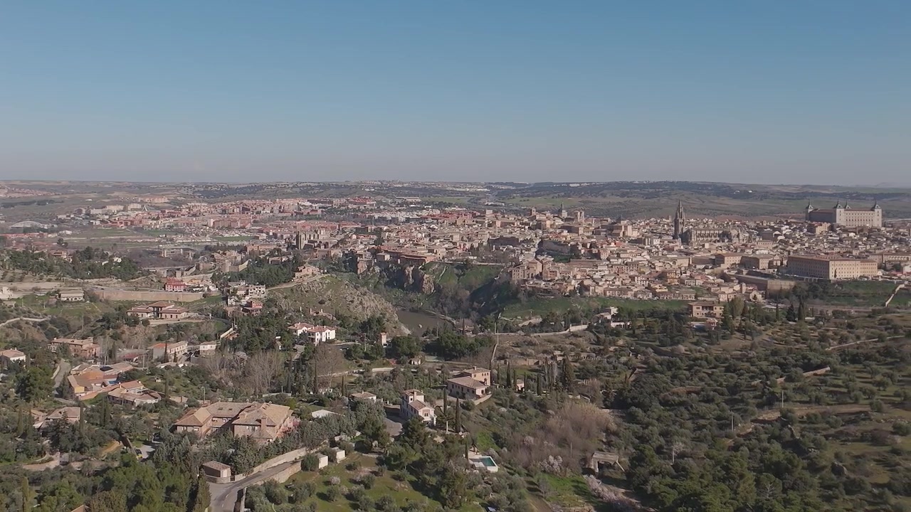 Riprese con drone che mostrano il centro storico di Toledo con un movimento panoramico fluido da sinistra a destra, rivelando la cattedrale, l'Alcázar, un tratto del fiume Tago e numerosi Cigarrales.