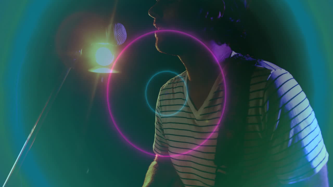 Singer performing into microphone on dark stage, surrounding neon flares animating music technology