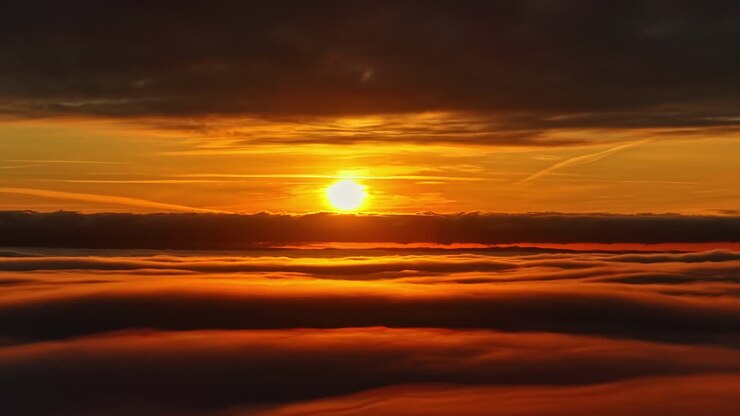 Tramonto panoramico sopra le nuvole con cielo dell'ora d'oro, sfondo di skyline con nuvole dalla trama di cotone che definisce il paesaggio naturale.