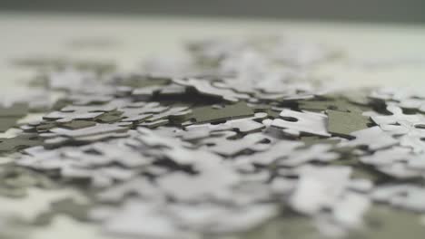 white and gray puzzle pieces laying randomly on a white surface spinning slowly with a dark background