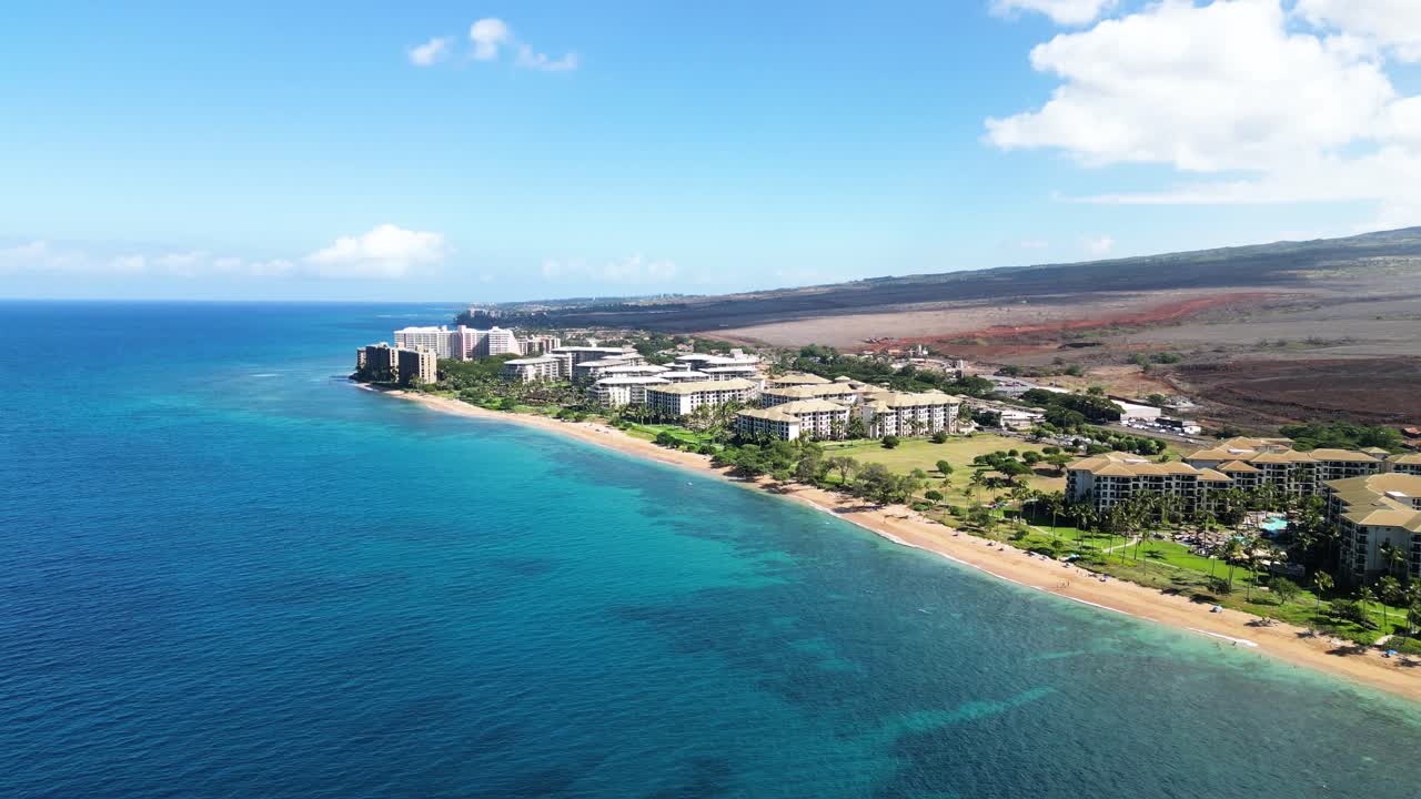Orbiting drone circles Lahaina shoreline, revealing resorts, harbor, and hills