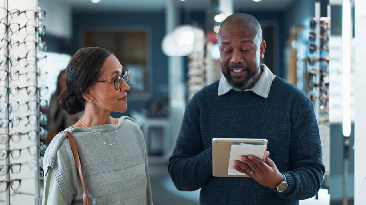 Optometrist explaining something on a tablet to a customer