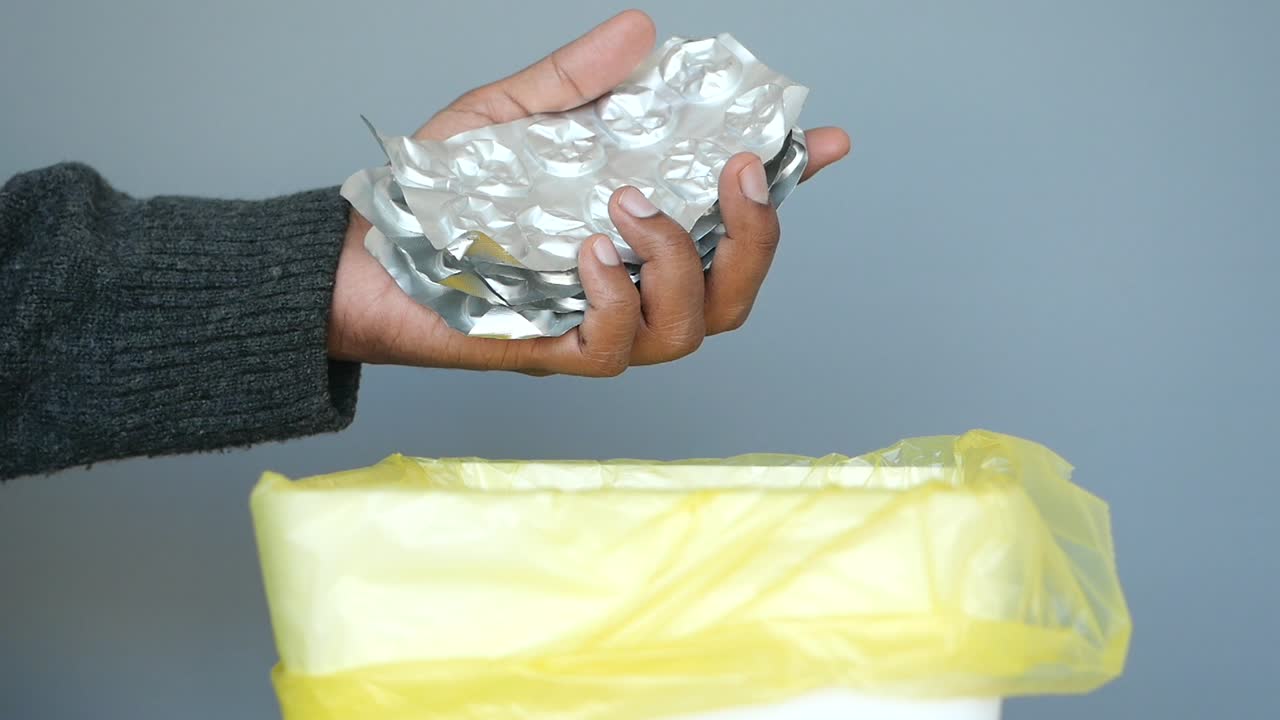 쓰레기통에서 약 패키지를 손으로 버리는 것