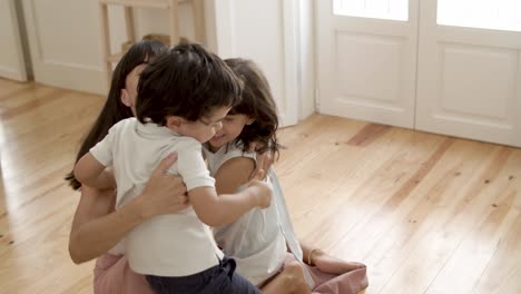 mamá feliz abrazando y besando a los niños pequeños