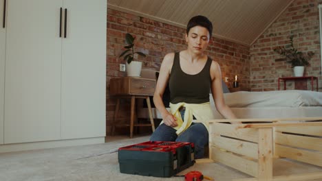 woman assembling wooden storage crate in bedroom