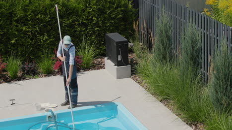 a worker cleans a swimming pool with a special vacuum cleaner. top view