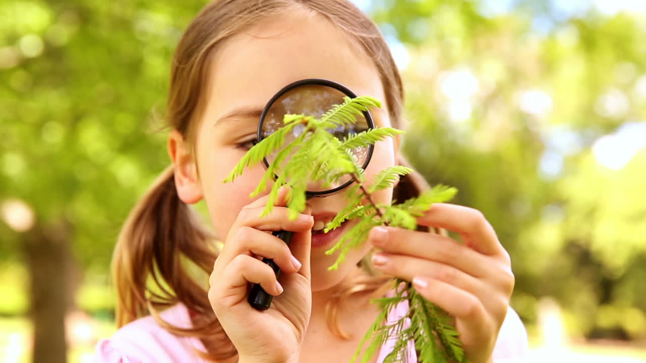 niña mirando la planta a través de una lupa