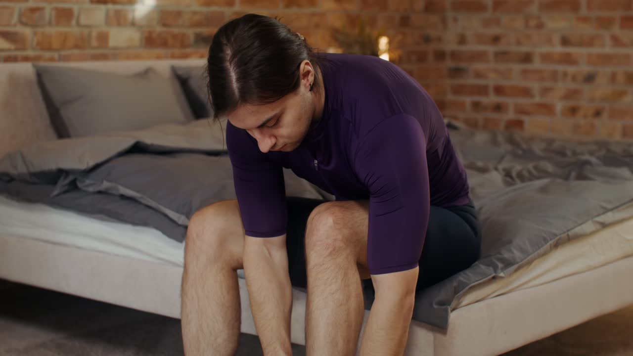 Man getting dressed in cycling clothes in his bedroom