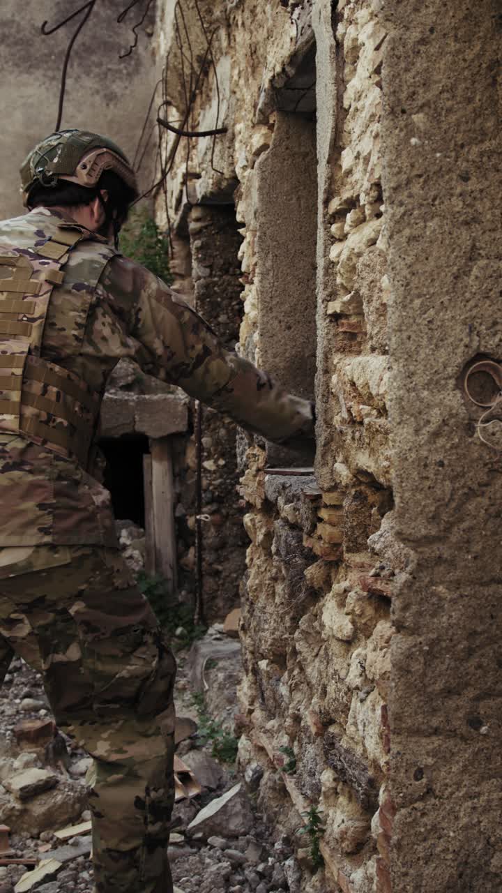 Soldier In Uniform Checks The Walls Of Destroyed Houses In The City