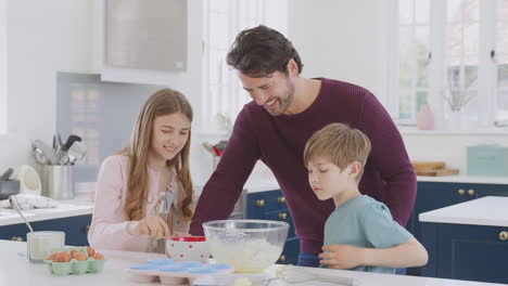 Padre-Con-Dos-Hijos-En-La-Cocina-De-Casa-Divirtiéndose-Horneando-Pasteles-Juntos