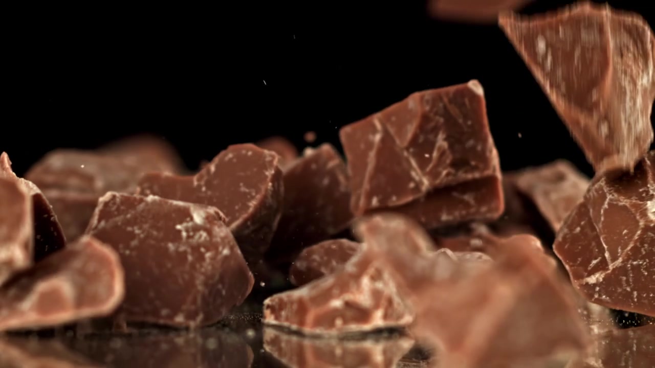 Pezzi di cioccolato al latte che cadono in super slow motion su sfondo nero