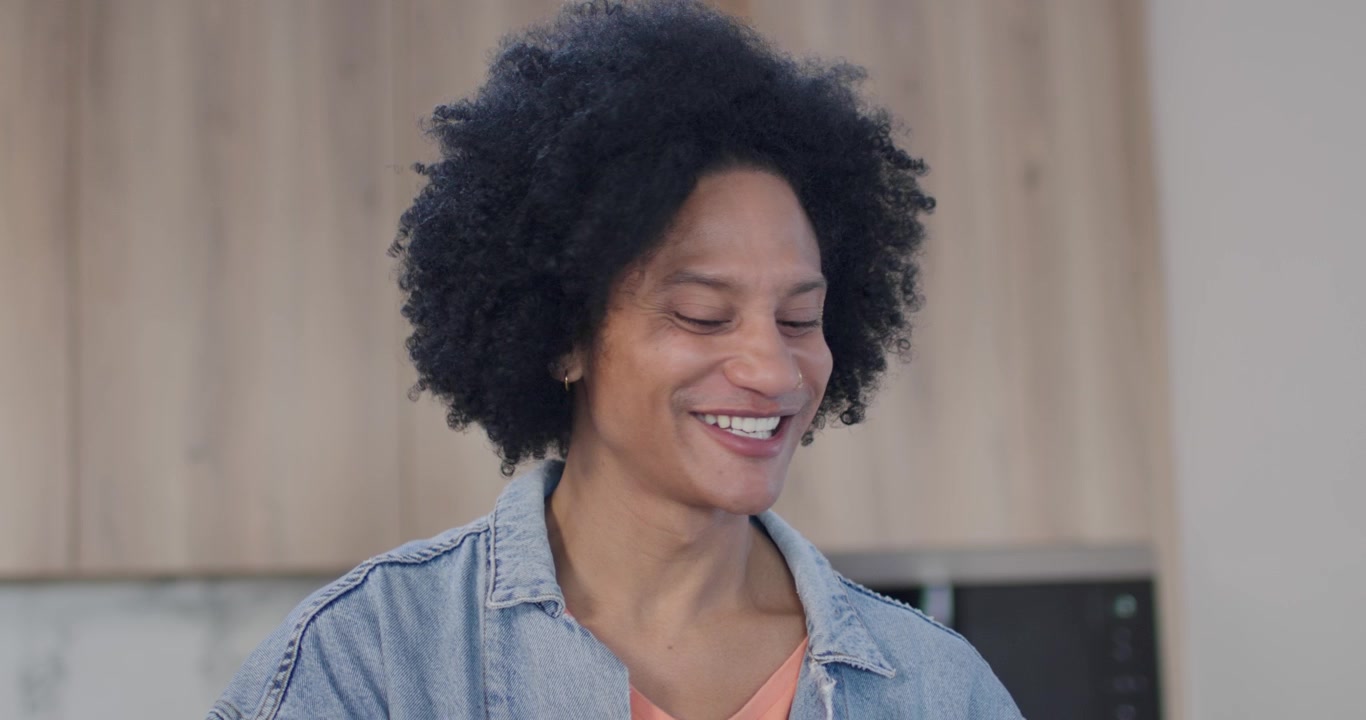 Homme afro-américain en veste en jean, souriant, répondant à une voix hors champ et vérifiant le comptoir.