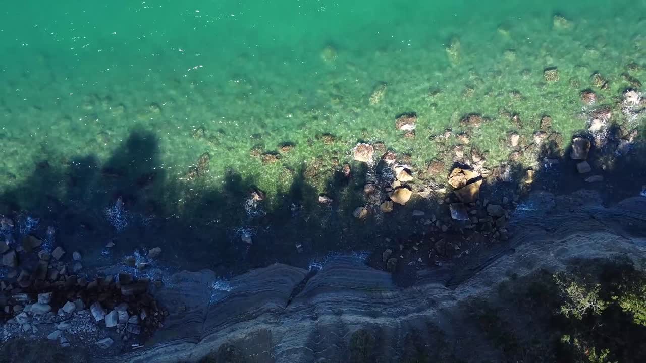 Ascending aerial of rock cliff shoreline