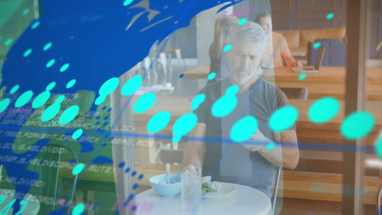 Mature adult man eating salad and checking smartphone in tech cafe, showing code and graphics