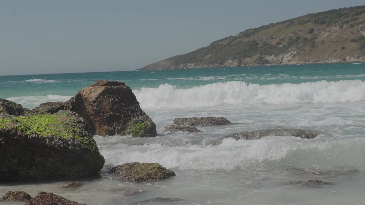 Onde dell'oceano che si infrangono contro rocce coperte di muschio sulla battigia
