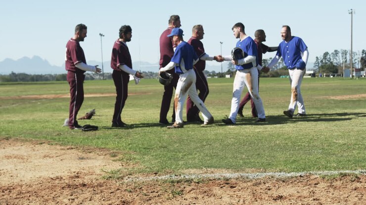 Giocatori di baseball multietnici che si stringono la mano a vicenda su un campo da baseball, al rallentatore