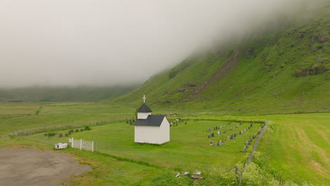 Cinematic-aerial-shot-of-a-small-graveyard-close-to-Utakleiv,-a-famous-surf-location-on-the-Lofoten-Islands-in-Norway,-Europe