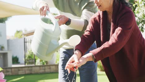 Happy-diverse-senior-couple-working-in-garden-on-sunny-day