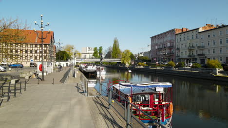 Aerial-view-of-fish-market-beside-docking-boats-on-Brda-River-during-sunny-day-in-Bydgoszcz,Poland