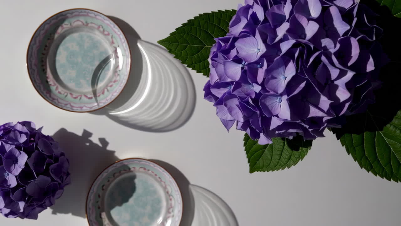 Overhead view of purple hydrangeas and decorative plates with shadows