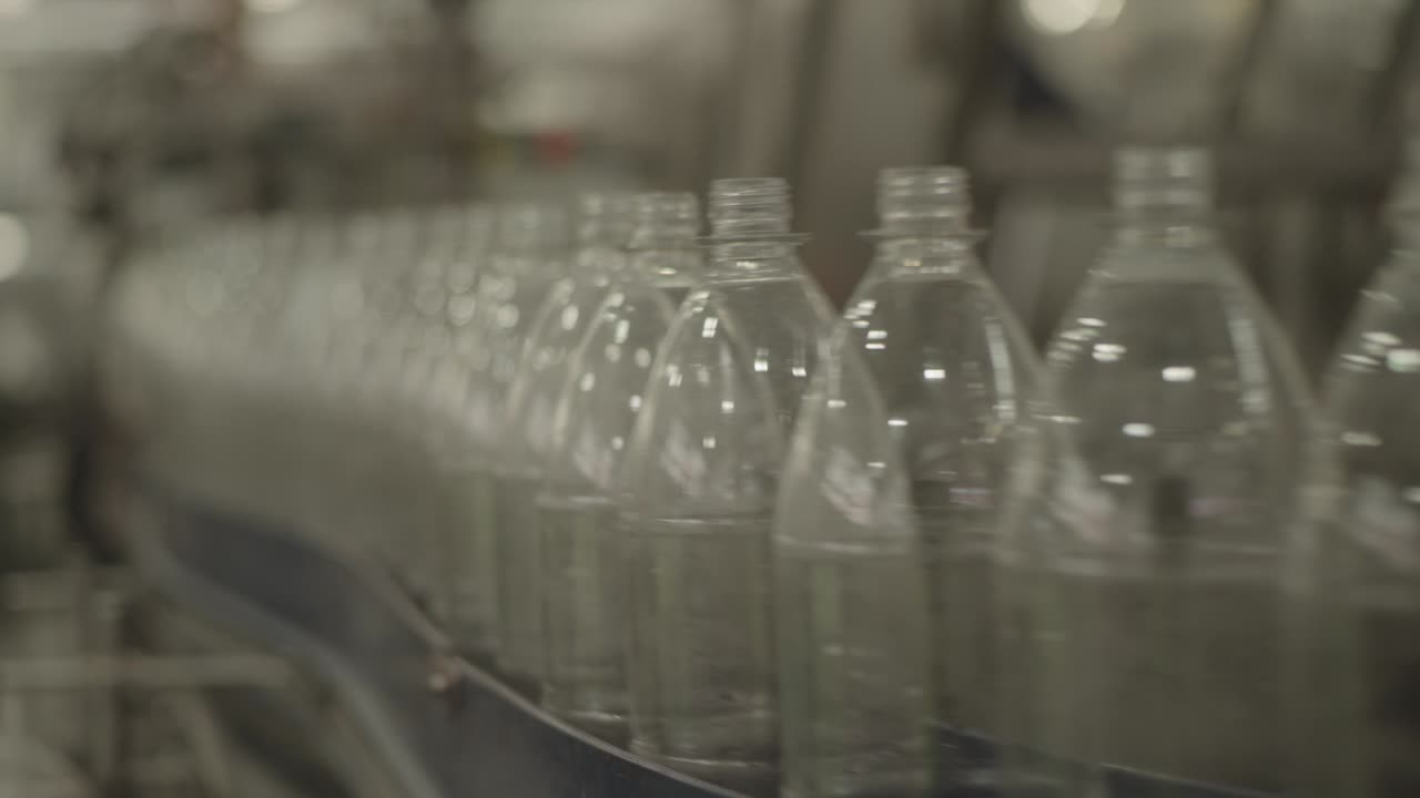 Fixed clip showing conveyor belt of translucent plastic bottle production line