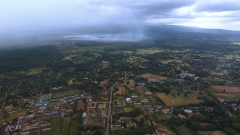 Aerial-view-of-a-village-in-rural-Africa,-tropical-wildfire-background---rising,-drone-shot