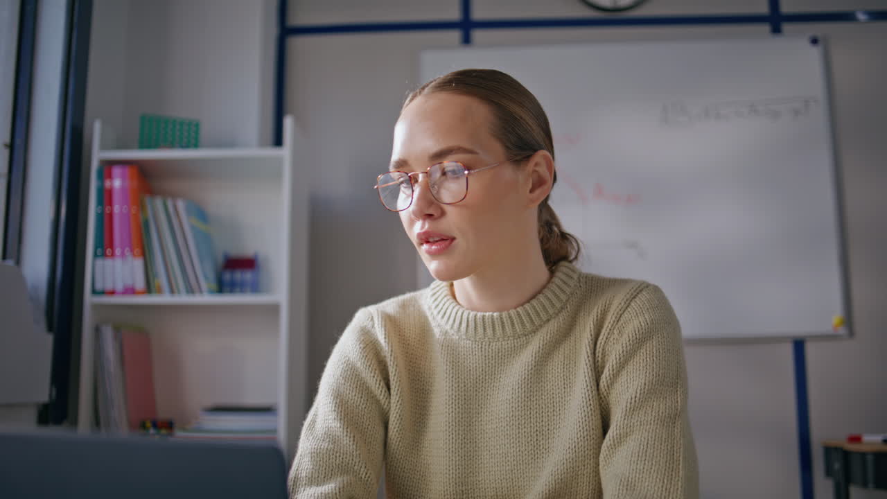 Tutor lady wearing glasses preparing online lesson at school workplace closeup