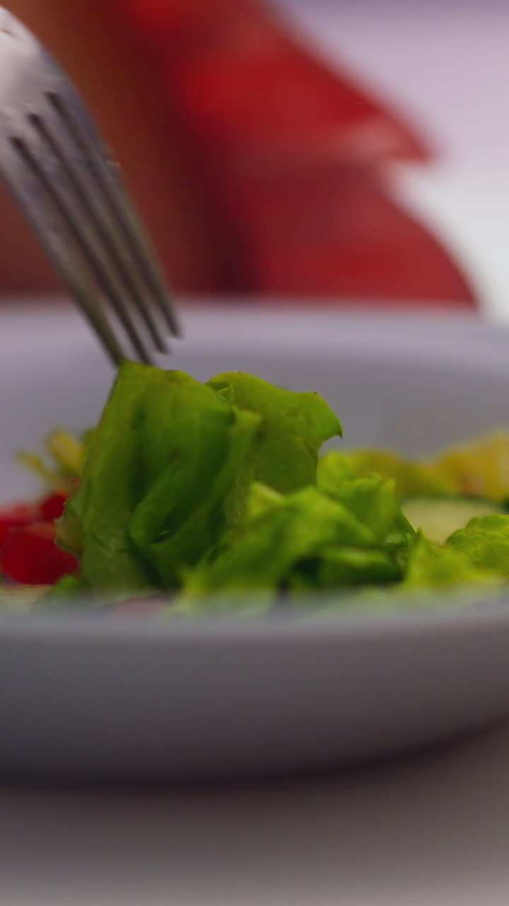 recogiendo una deliciosa ensalada fresca con un tenedor de plata brillante en el plato en la mesa blanca durante una cena aburrida vista extrema de cerca cámara lenta