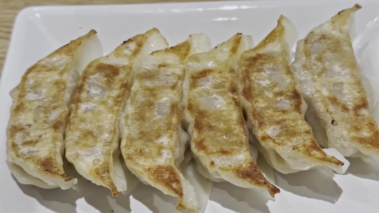 Close-up of golden fried gyoza served with savory dipping sauce, showcasing a crispy wrapper and juicy filling in an appetizing Japanese-style appetizer.