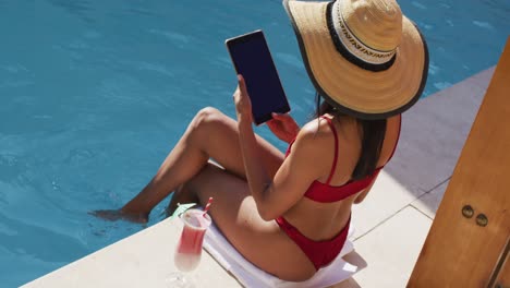 Mixed-race-woman-sitting-by-a-pool-at-home