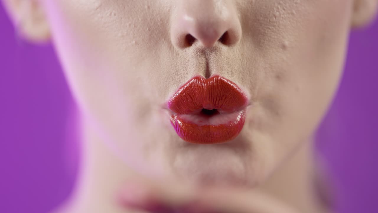 mujer con lápiz labial rojo oscuro enviando besos, boca seductora de cerca