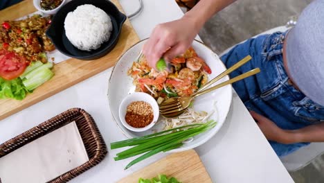 person garnishing pad thai with lime and spices