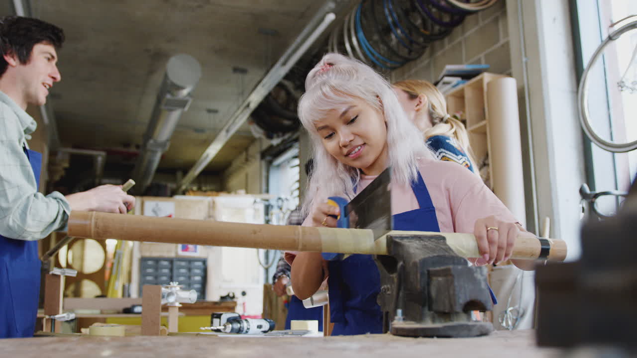 Multi-Cultural Team Of Trainees In Workshop Assembling Hand Built Bicycle Frame Together