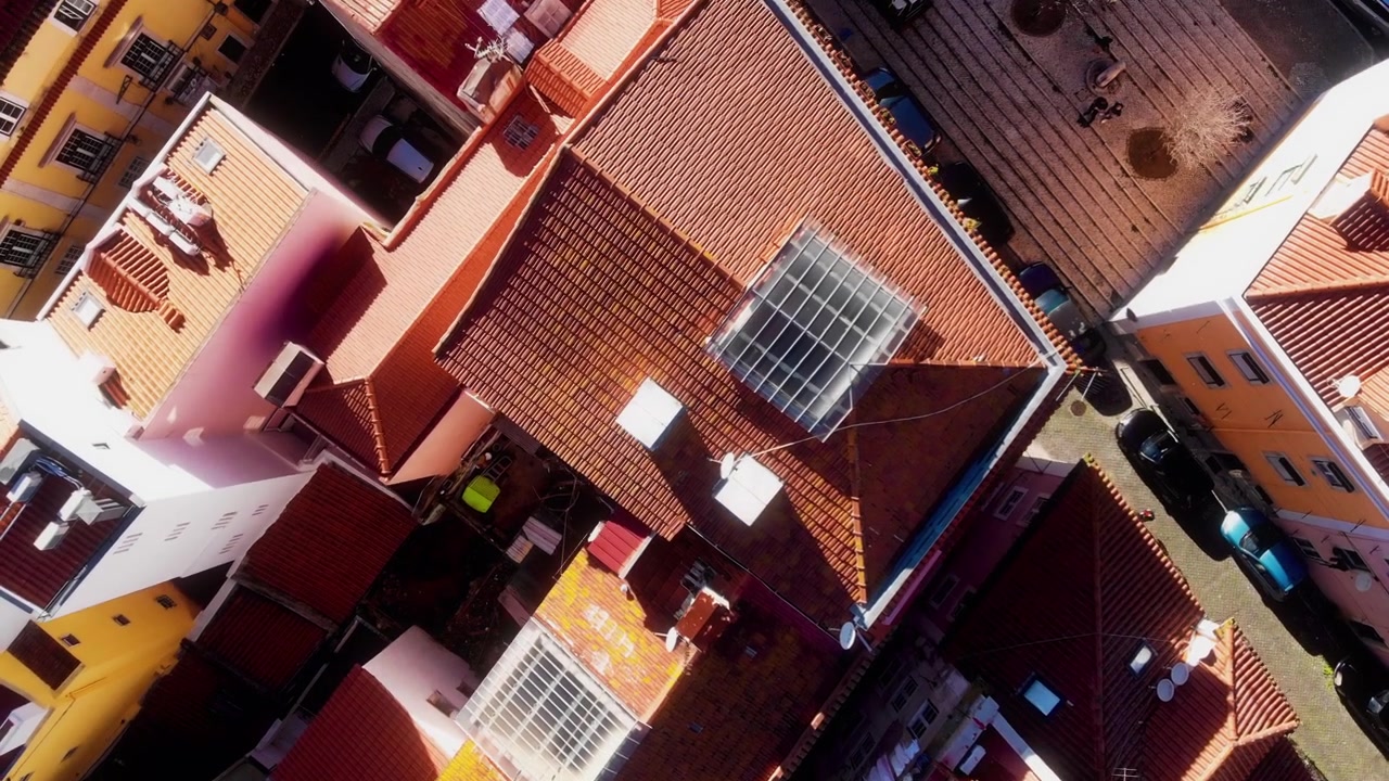 Drone flies above sunlit rooftops and narrow streets in Lisbon