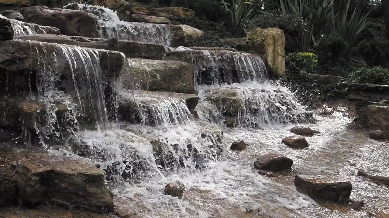 cascada cayendo por las rocas en un jardín ajardinado
