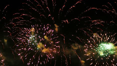 coloridos fuegos artificiales reales celebran la víspera de año nuevo con un desenfoque abstracto de brillo dorado con luces bokeh en el cielo nocturno