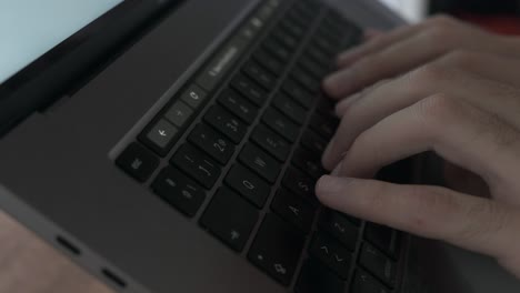 slow-motion close-up of male fingers typing on grey laptop