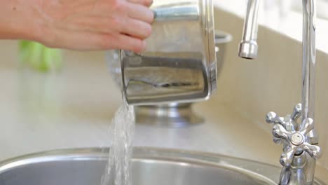 woman straining pot of water into the sink