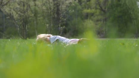 retrato de una linda chica caucásica despreocupada acostada en la hierba en el parque, cámara lenta estática con poca profundidad de campo