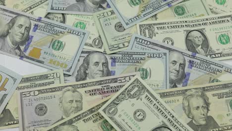 dollar bills fall on the table with american dollars of different denominations