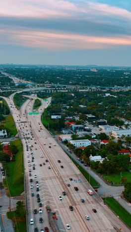 going up above the highway with multiple vehicles driving by. panoramic view of the low rise urban area in miami, florida, usa. vertical video
