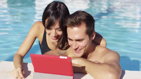 Smiling-couple-in-swimming-pool-use-digital-device