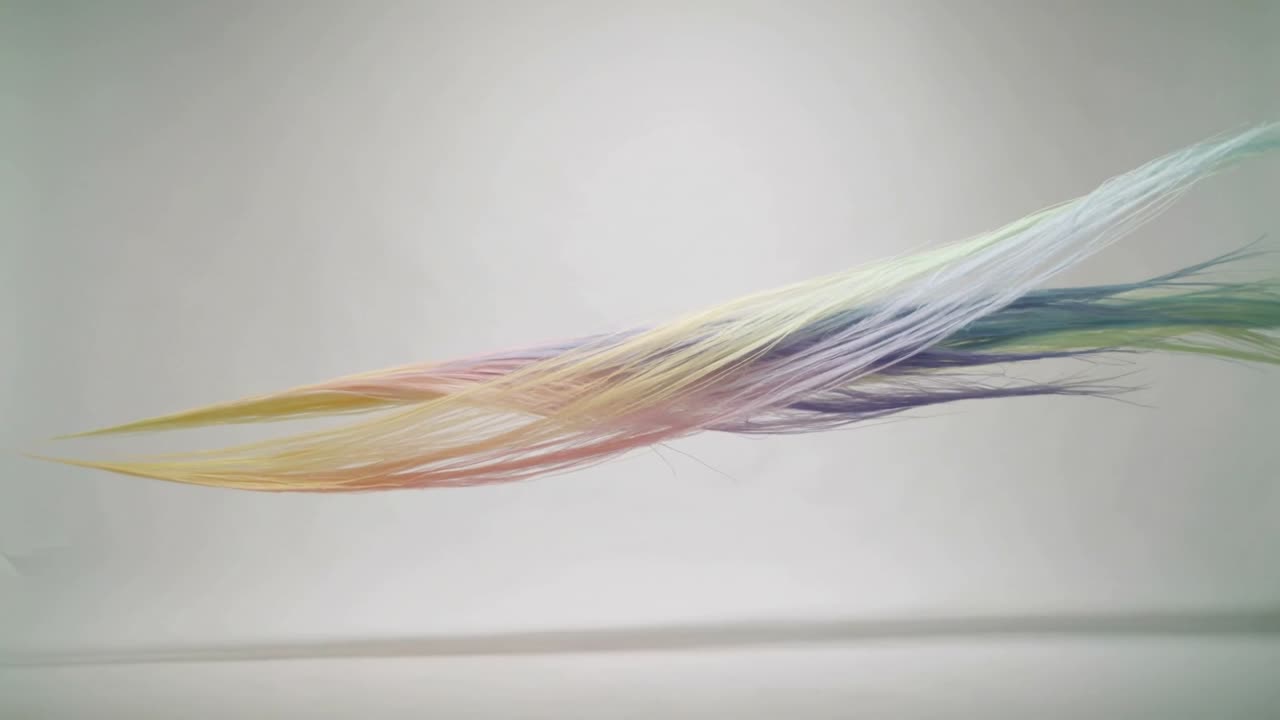 Fra venstre kommer et pastel filamentbånd frem, forlænges og flettes mod højre på en lys baggrund.
