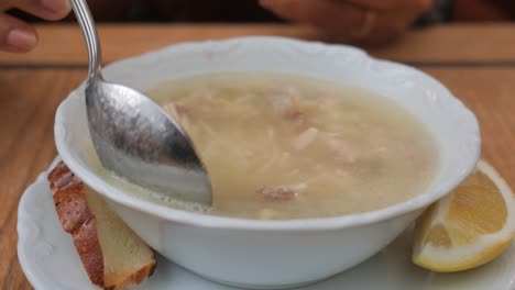 a bowl of turkish chicken soup with lemon and bread