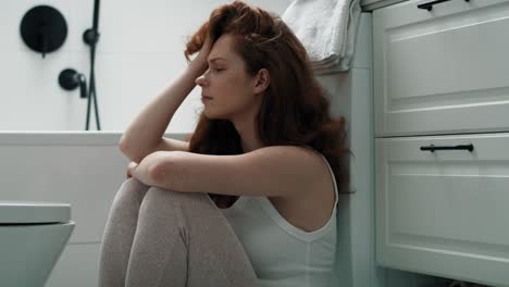 Caucasian-woman-with-problems-sitting-on-the-floor-in-the-bathroom.