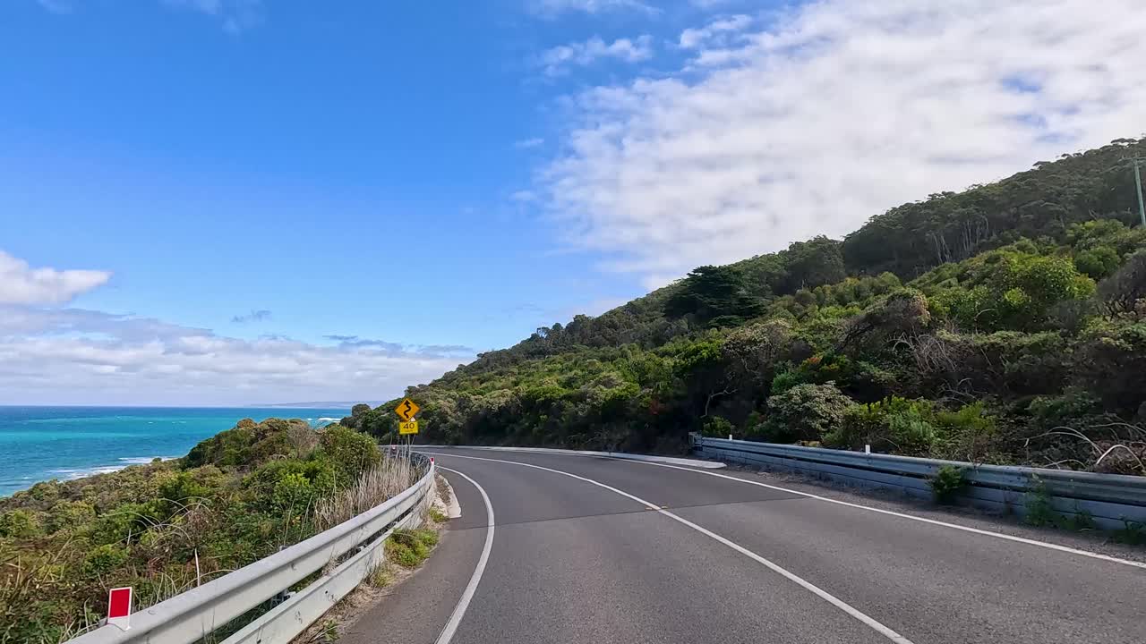 A picturesque drive along the Great Ocean Road with coastal views, lush greenery, and clear blue skies captured in vibrant daylight