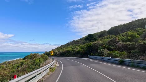 a picturesque drive along the great ocean road with coastal views, lush greenery, and clear blue skies captured in vibrant daylight