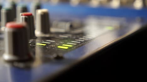 close up view of mixer soundboard with knobs and flashing green light indicators in modern recording studio. slow motion