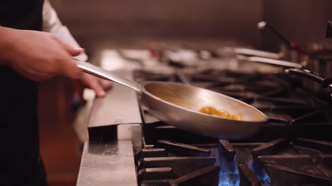 Il Cuoco Salta la Padella d'Acciaio con la Pasta Avanti e Indietro Mentre la Pasta Cuoce sul Fuoco